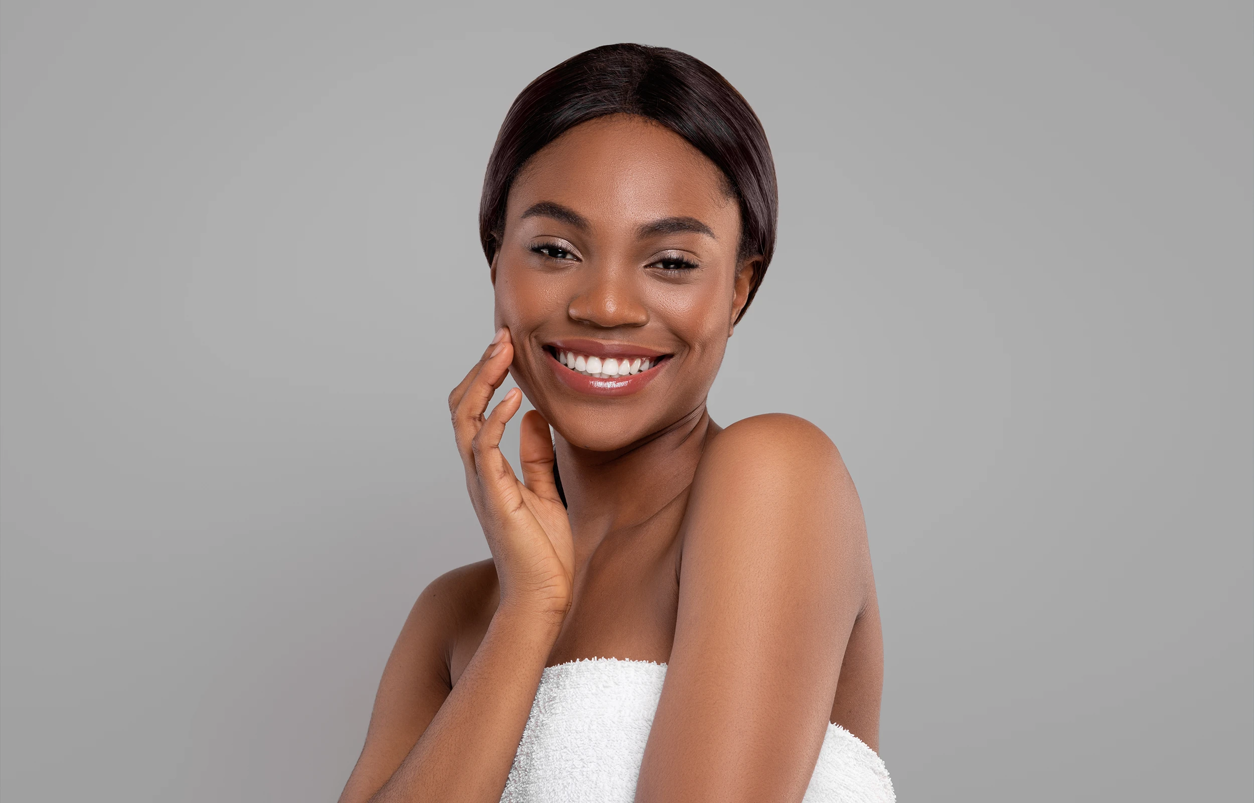 Smiling woman with smooth skin wrapped in a white towel